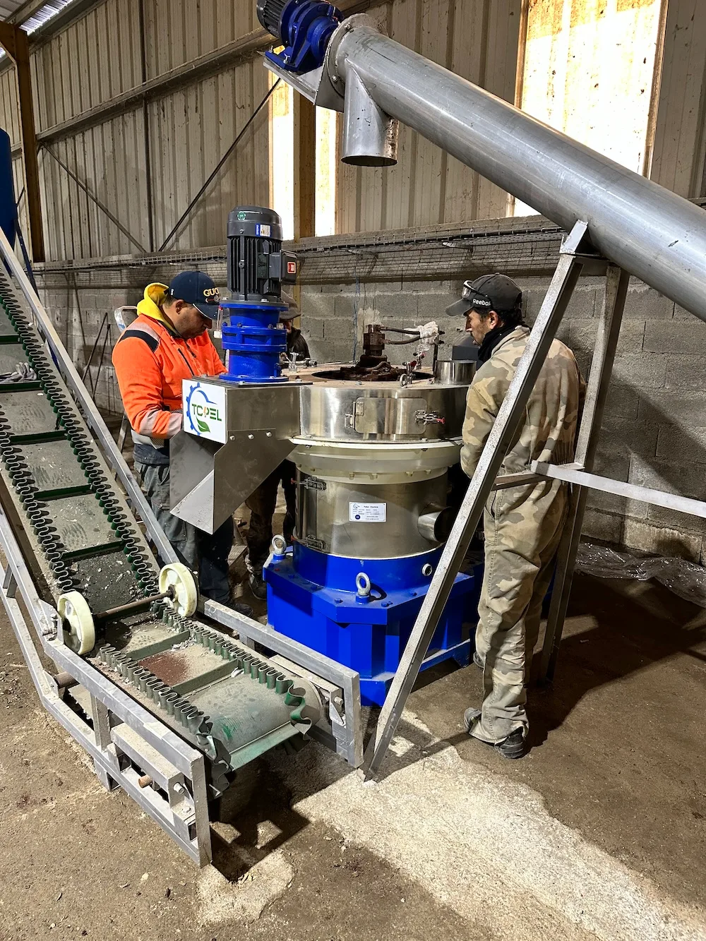 Technicians inspecting a vertical ring die pellet mill during maintenance