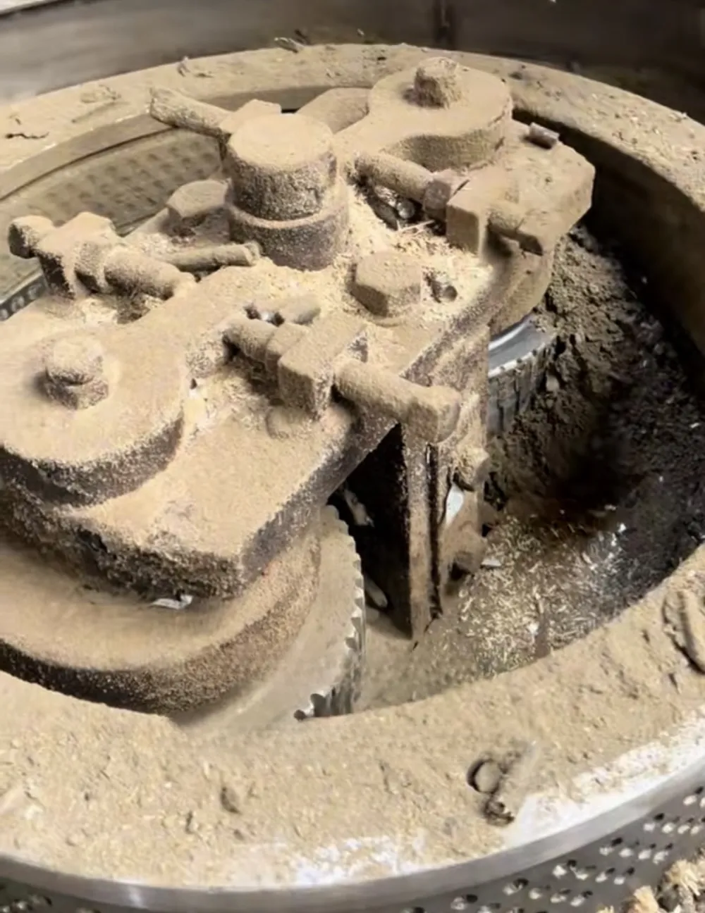 Sawdust buildup around rollers in an isolated wood pellet mill chamber